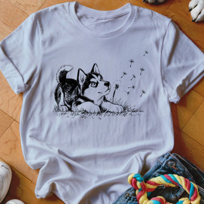 A white crewneck t-shirt featuring a black line drawing of a puppy watching floating dandelion seeds.