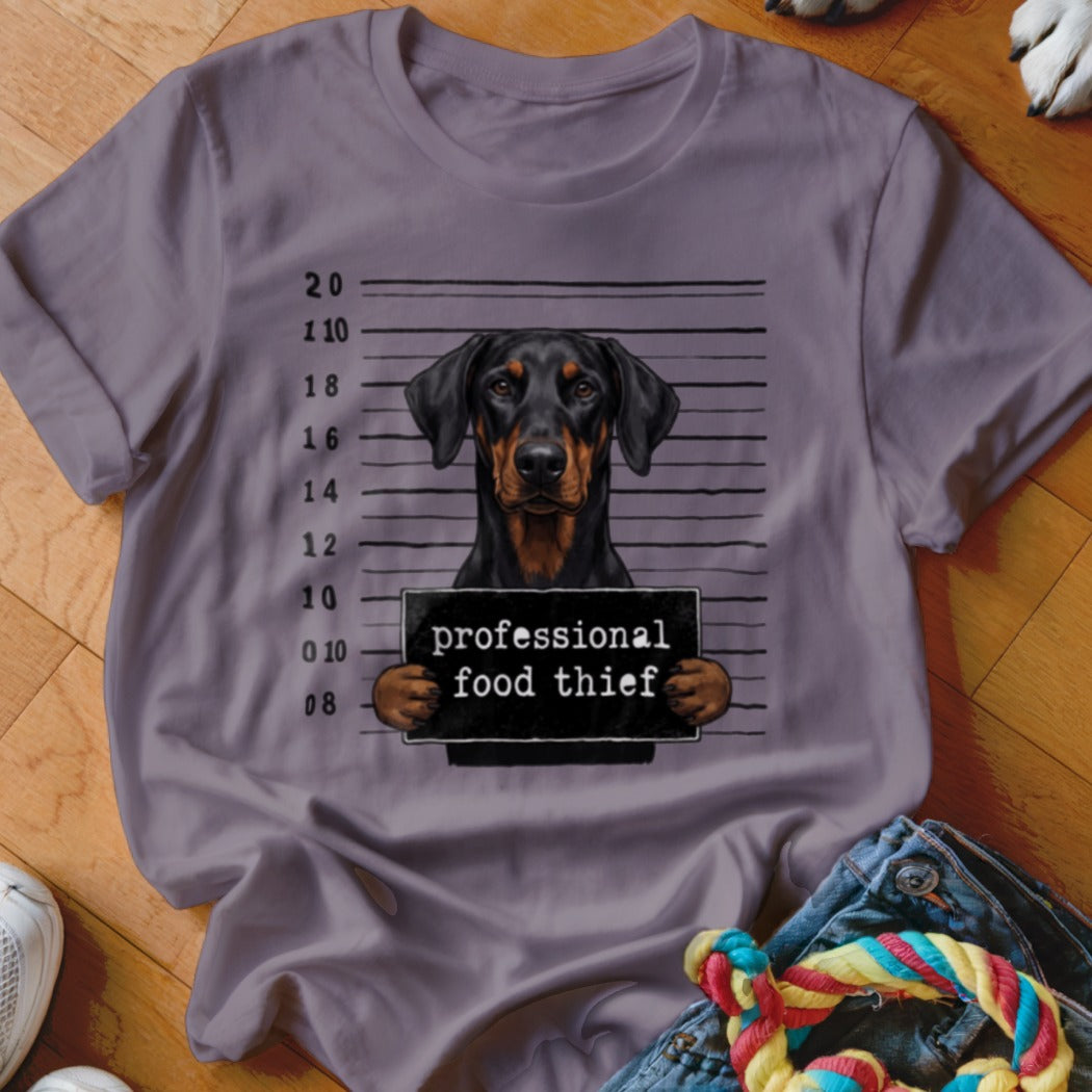 Doberman police mugshot with "professional food thief" sign.