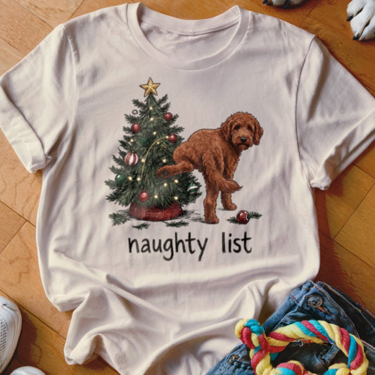 Light t-shirt with a drawing of a brown dog near a Christmas tree, text reads "naughty list".
