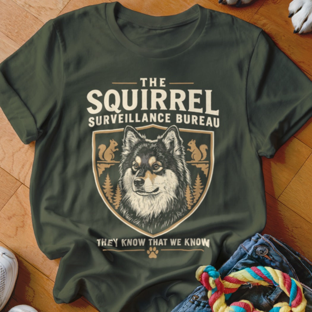 Dark green t-shirt with a graphic of a dog, squirrels, and the text The Squirrel Surveillance Bureau.