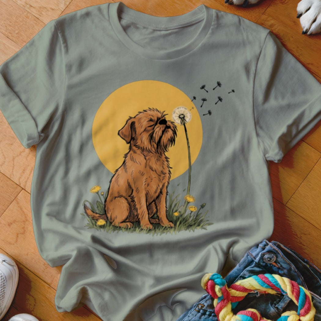 Sage green t-shirt featuring a cartoon illustration of a brown dog blowing dandelion seeds.