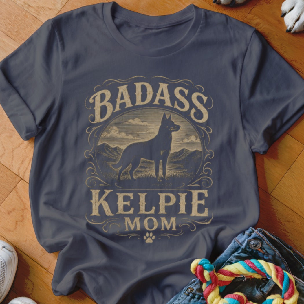 "Badass Kelpie Mom" text with a silhouette of a Kelpie dog on a dark blue t-shirt.