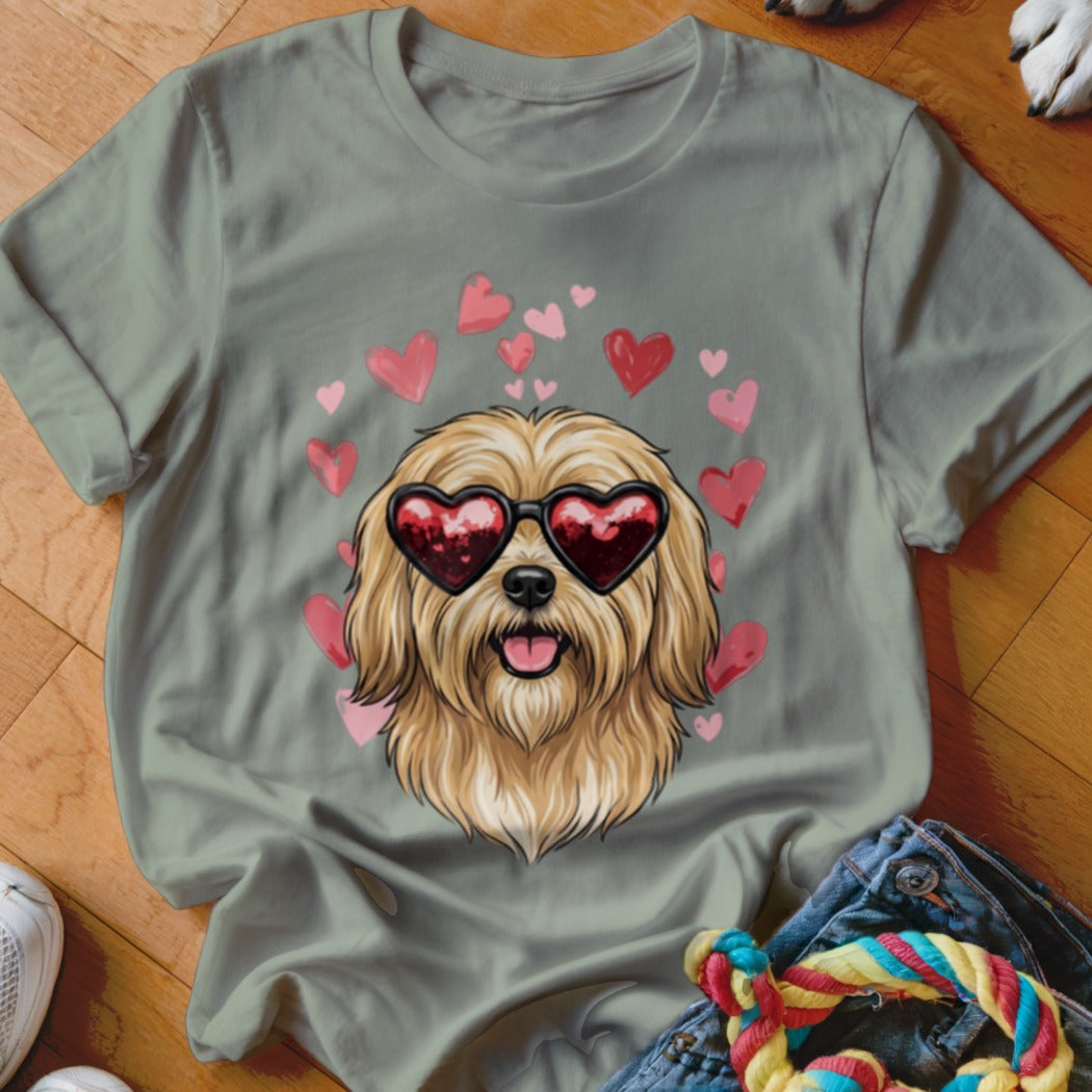 A sage green t-shirt featuring an illustration of a fluffy dog wearing heart-shaped sunglasses surrounded by pink hearts.