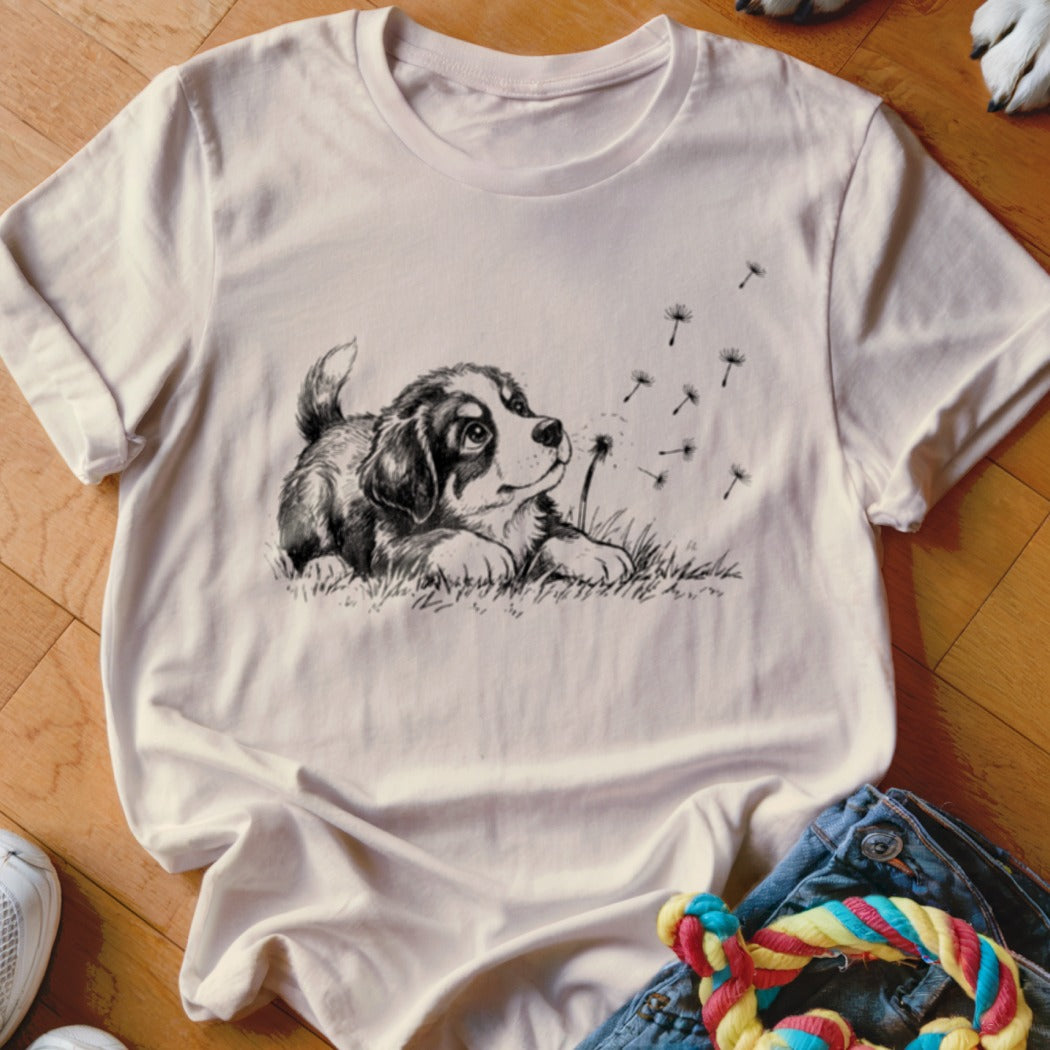 Light pink crewneck t-shirt featuring a black and white sketch of a puppy blowing dandelion seeds.