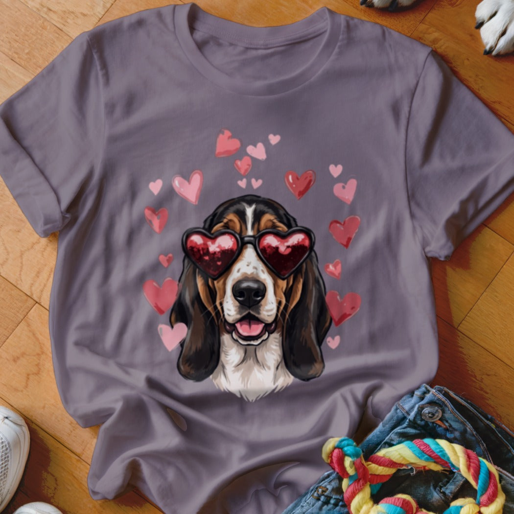 A purple t-shirt featuring a basset hound wearing heart-shaped sunglasses surrounded by pink hearts.