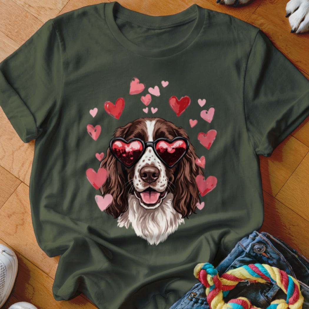 Dark green t-shirt featuring a brown and white spaniel wearing heart-shaped sunglasses surrounded by floating pink hearts.