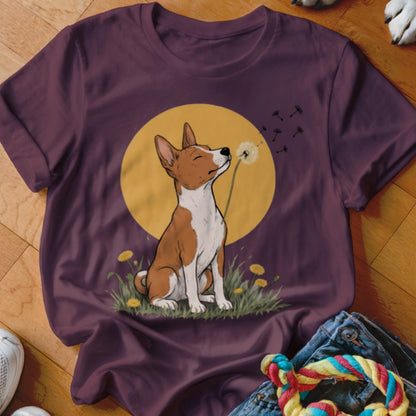 A dark purple short-sleeved t-shirt featuring a cartoon illustration of a Basenji dog blowing dandelion seeds in front of a yellow circle.