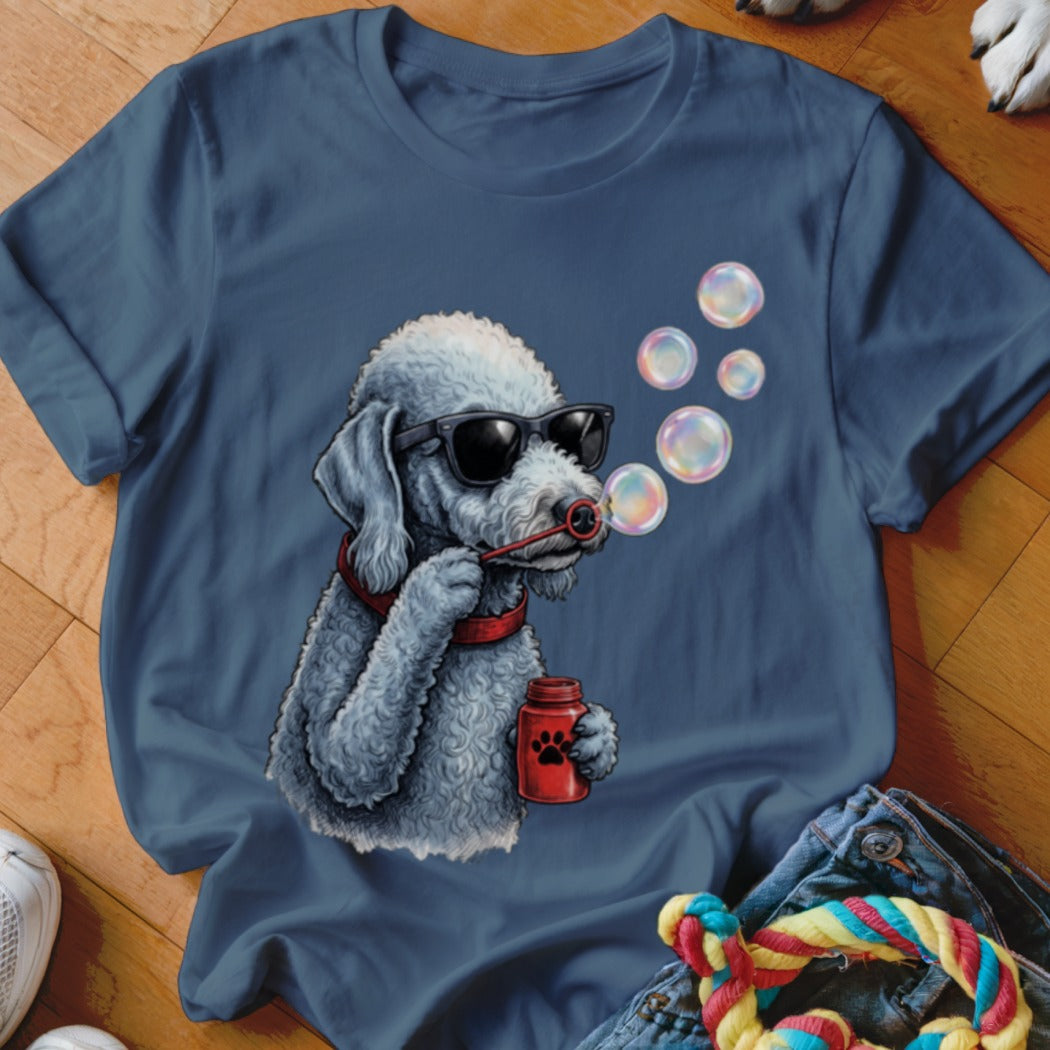 A dark blue t-shirt printed with a graphic of a white poodle wearing sunglasses and blowing bubbles.