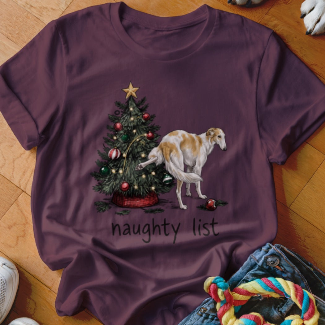 A dark purple t-shirt featuring a graphic of a dog lifting its leg on a Christmas tree above the text "naughty list."