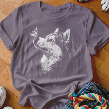 A purple t-shirt featuring a white graphic of a husky looking at a butterfly on its nose.
