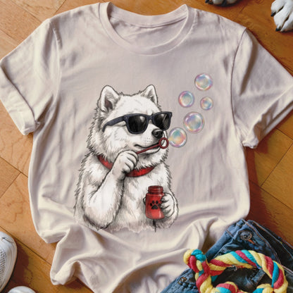 A light beige t-shirt featuring a graphic of a white dog wearing sunglasses and blowing bubbles.