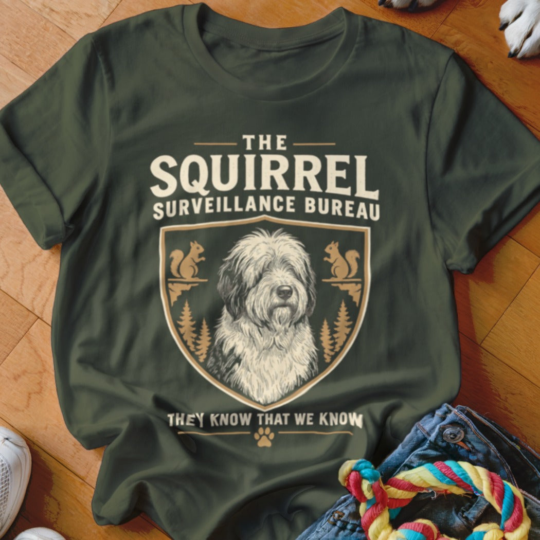 Dark green t-shirt featuring a crest with a shaggy dog, squirrels, pine trees, and text reading The Squirrel Surveillance Bureau.