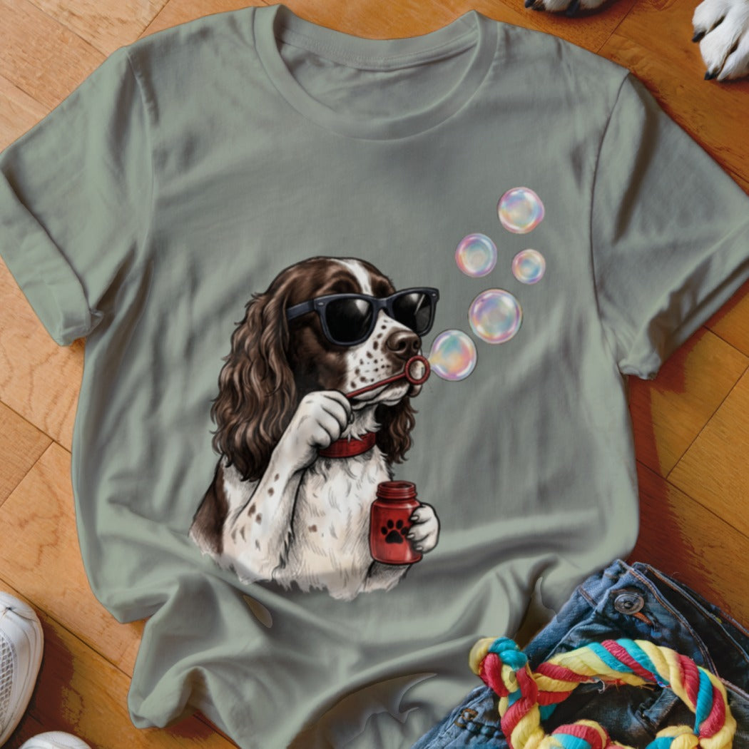 Sage green crewneck t-shirt featuring a graphic of a brown and white spaniel wearing sunglasses and blowing bubbles.