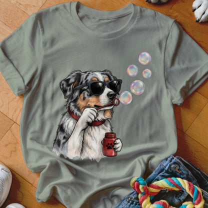 An olive green t-shirt featuring a graphic of an Australian Shepherd wearing sunglasses and blowing bubbles.