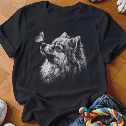 A black t-shirt featuring a white sketch graphic of a Pomeranian dog looking at a butterfly.