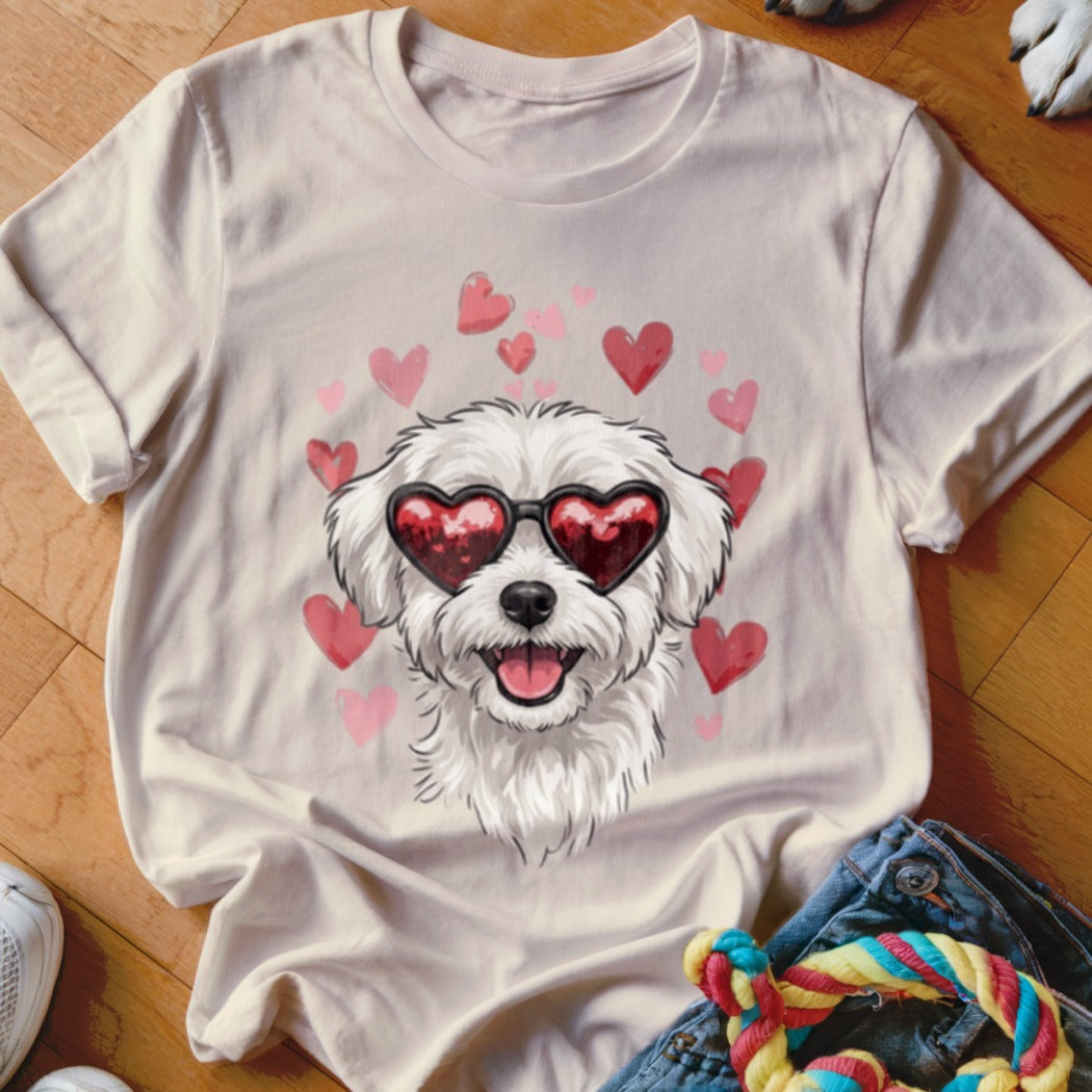 A light beige t-shirt with a graphic of a white dog wearing heart-shaped sunglasses surrounded by pink hearts.