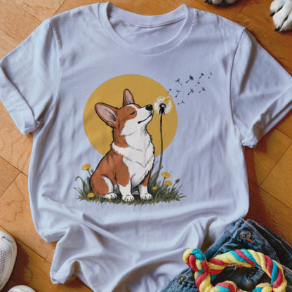 White crewneck t-shirt featuring a cartoon illustration of a corgi blowing dandelion seeds against a yellow sun.