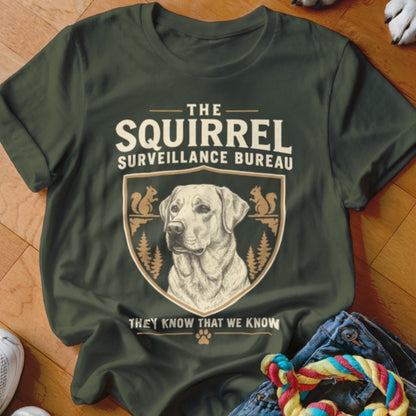 Dark green crewneck t-shirt featuring a crest with a dog portrait and the text The Squirrel Surveillance Bureau.