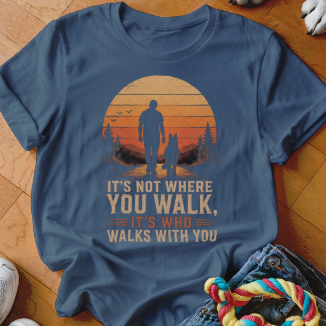 Blue t-shirt with graphic of person walking dog at sunset and text "It's not where you walk, it's who walks with you."