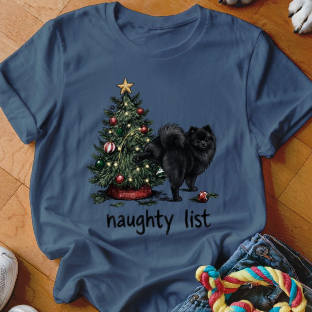 Black Pomeranian dog near Christmas tree with "naughty list" text.