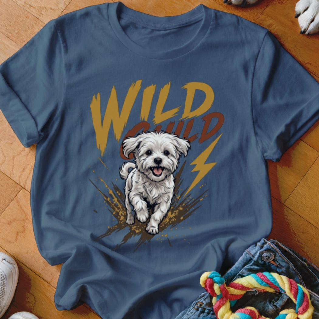 A dark blue t-shirt featuring a graphic of a white fluffy dog running amid mud splatters and lightning bolts, with the words "WILD CHILD" printed above.