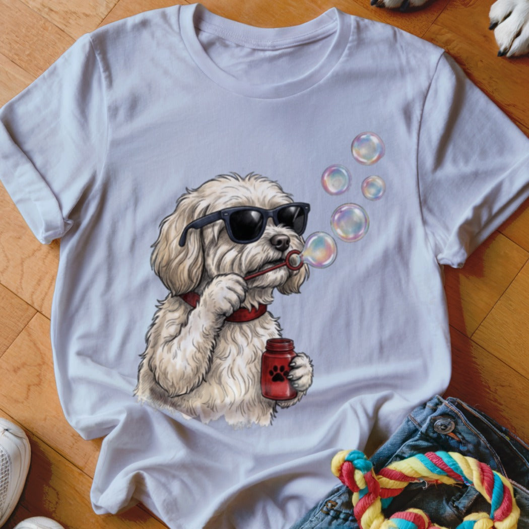 A white t-shirt featuring a cartoon illustration of a fluffy dog wearing sunglasses and blowing bubbles.