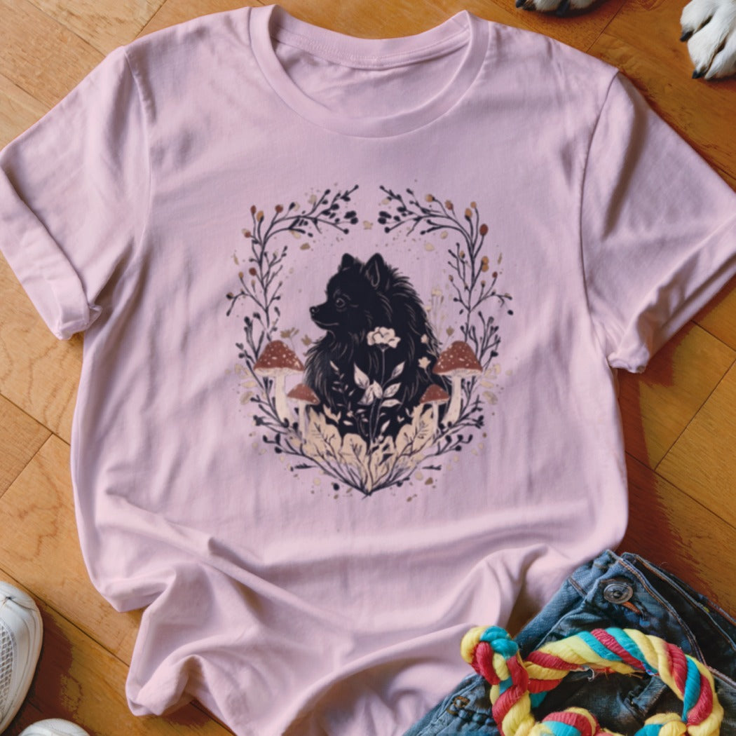 Light pink t-shirt featuring a graphic of a black dog surrounded by mushrooms and leaves.