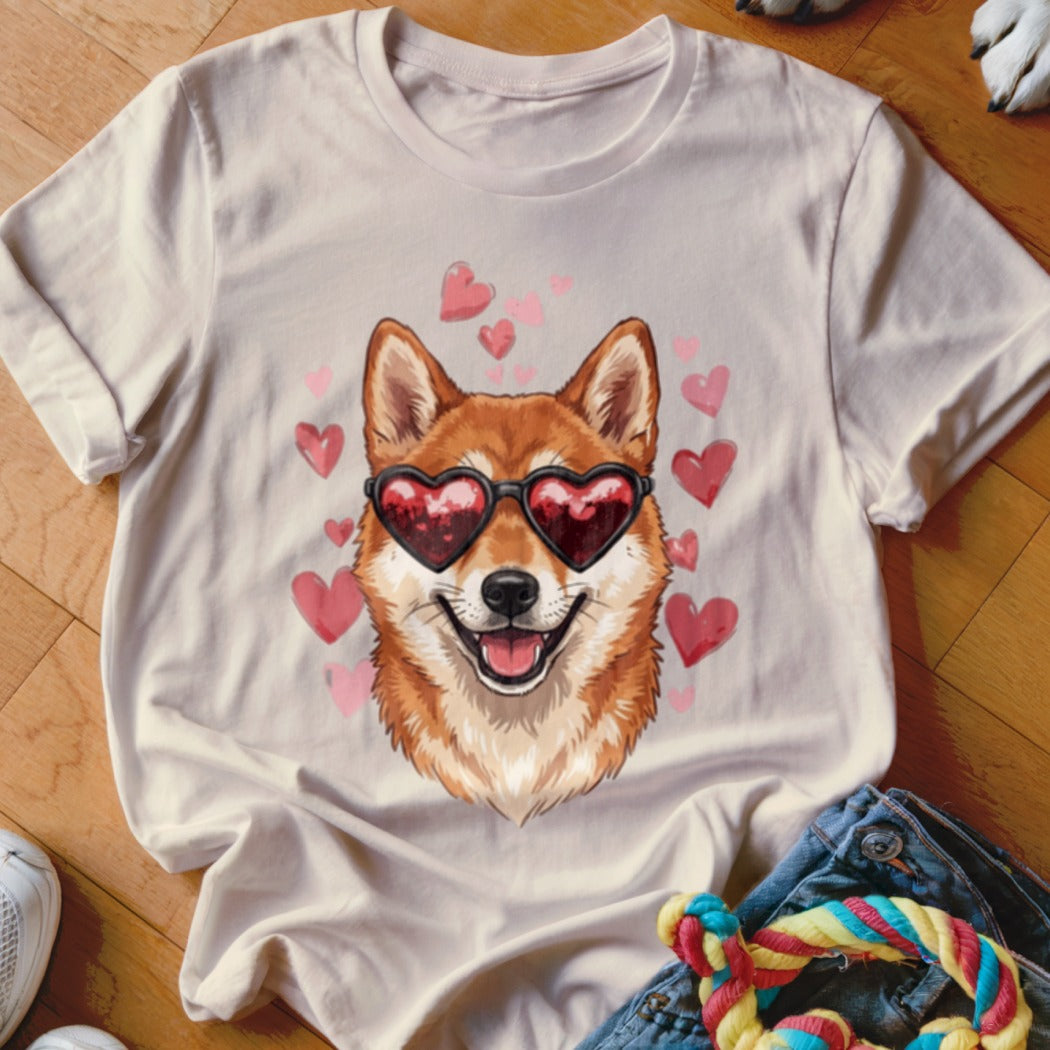 A cream-colored t-shirt with a graphic of a Shiba Inu dog wearing heart-shaped sunglasses, surrounded by pink hearts.