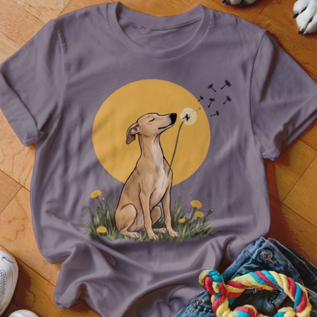 A purple t-shirt featuring an illustration of a brown dog sitting in grass blowing a dandelion.
