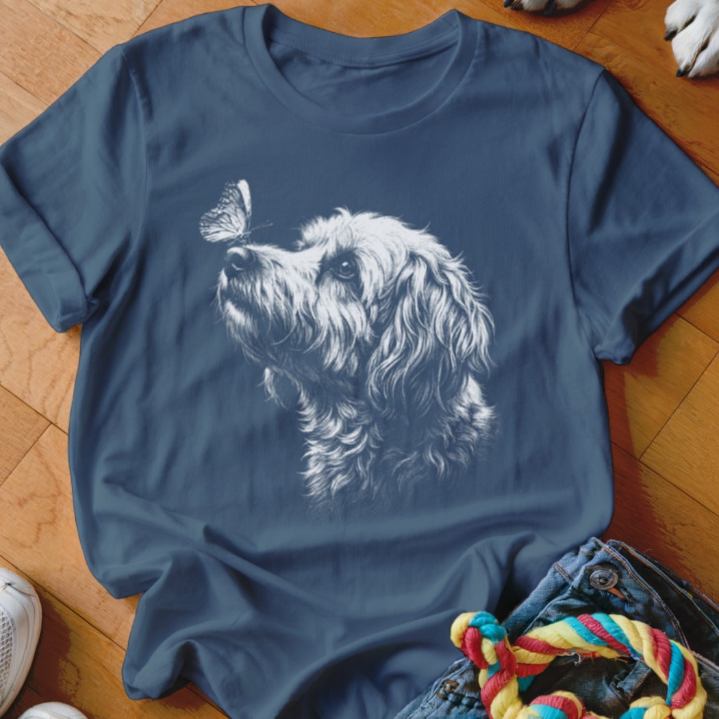 Blue crewneck t-shirt featuring a white graphic of a fluffy dog looking at a butterfly.