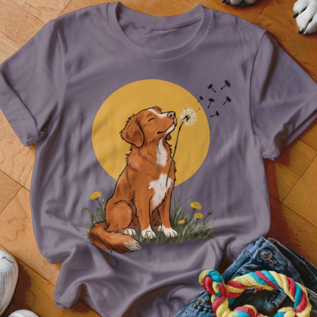A grey t-shirt featuring an illustration of a brown and white dog blowing a dandelion against a yellow circle background.