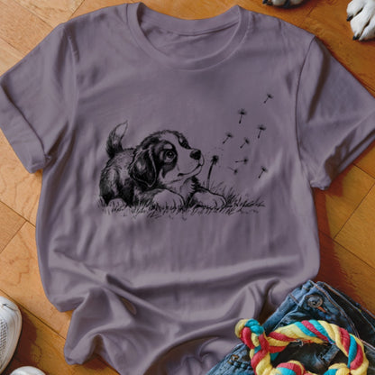 Muted purple crewneck t-shirt featuring a black and white sketch of a puppy watching dandelion seeds blow away.