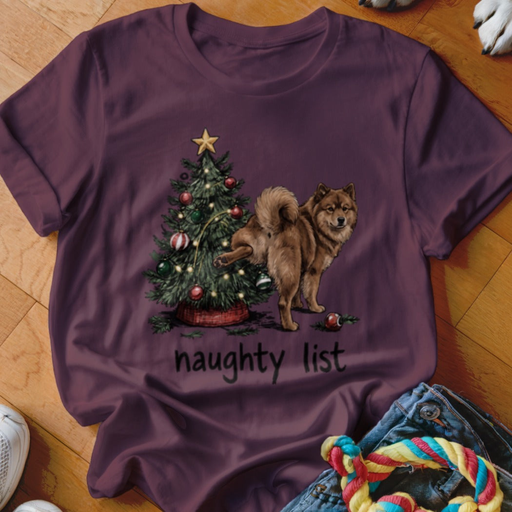 Brown dog near Christmas tree with text "naughty list" on t-shirt.