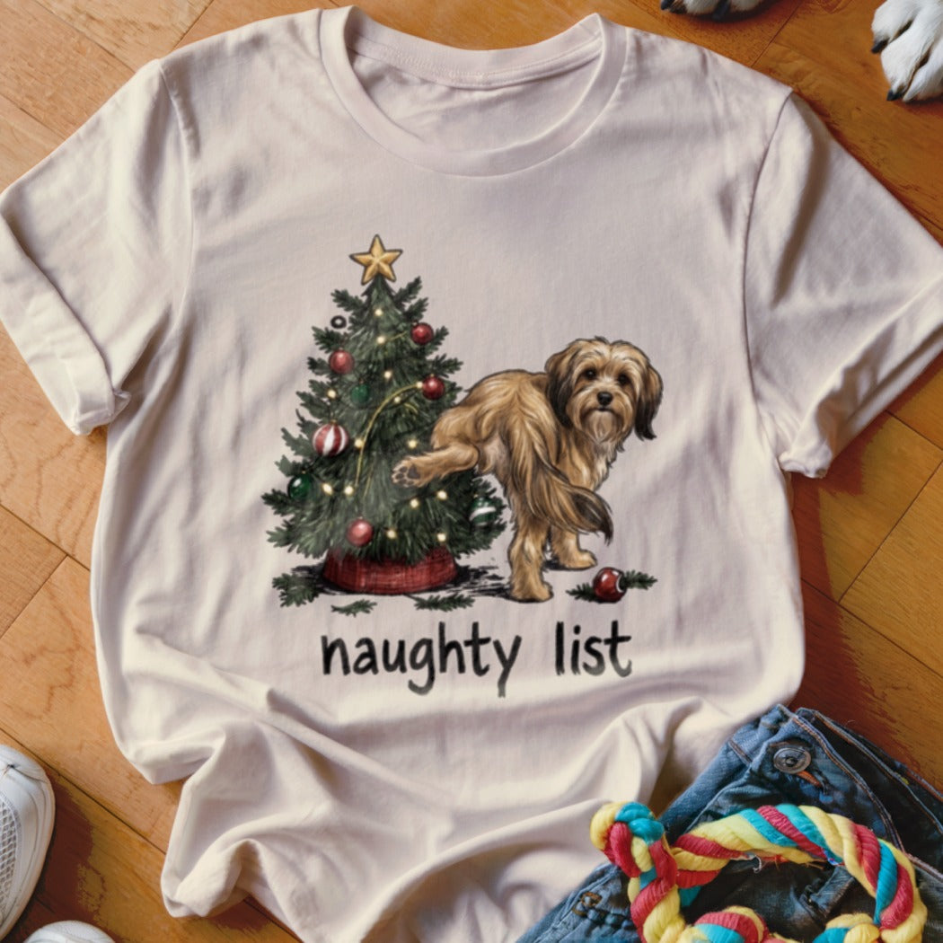 Light cream t-shirt with a dog near a Christmas tree, reading "naughty list".