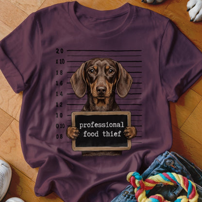 Dachshund dog in mugshot holding a sign that says "professional food thief."