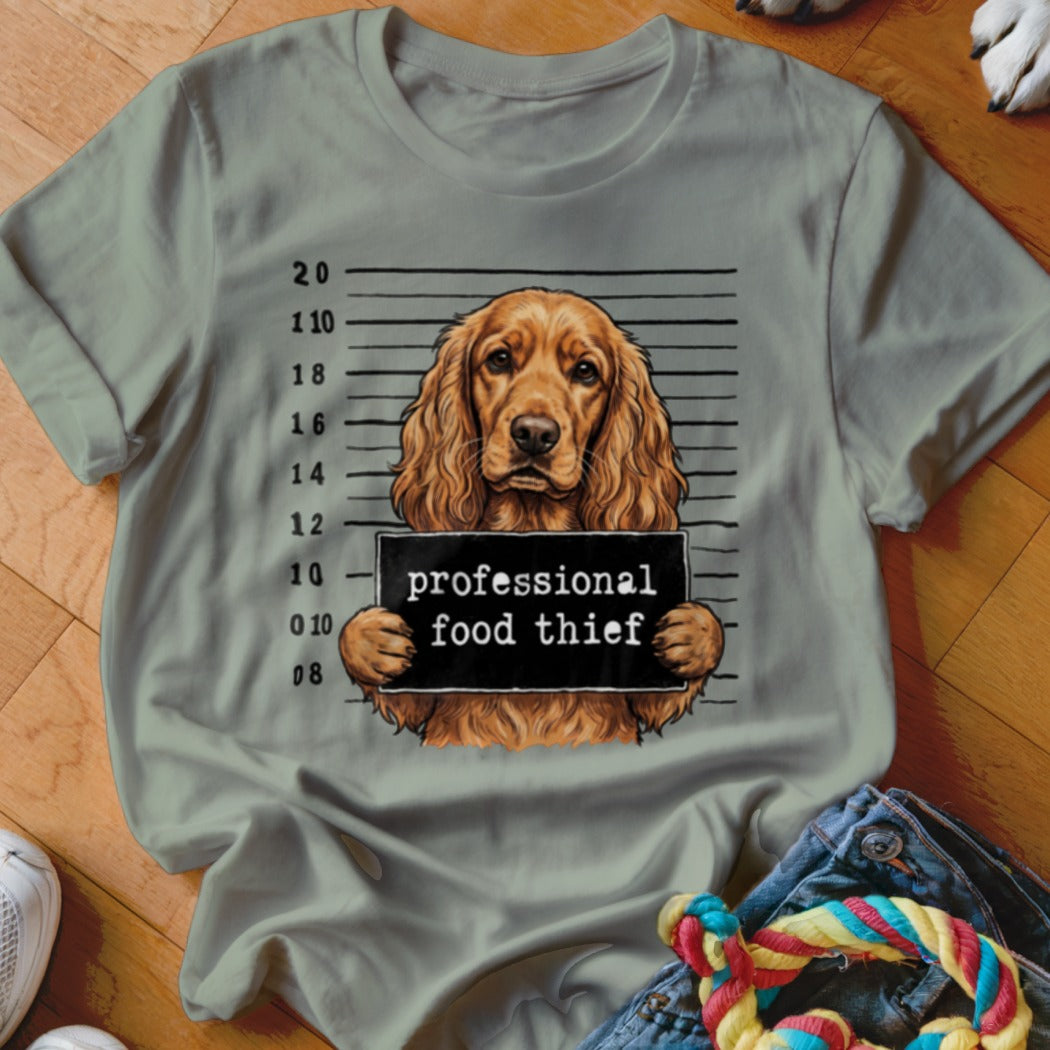 Dog mugshot graphic with text "professional food thief" on a light gray t-shirt.