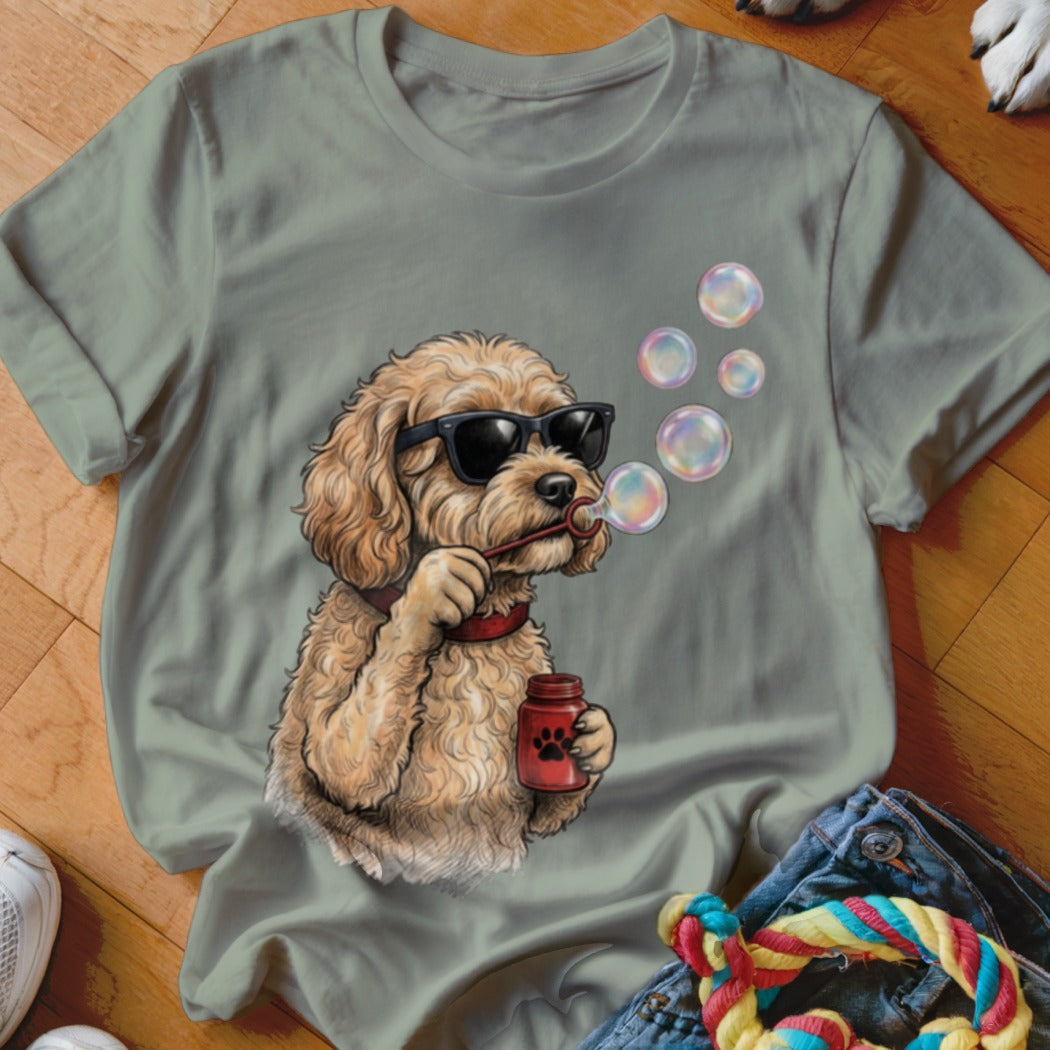 Sage green t-shirt featuring a graphic of a fluffy dog wearing sunglasses and blowing bubbles.