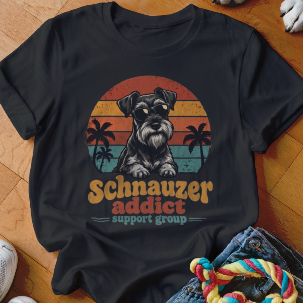 A black t-shirt features a graphic of a Schnauzer wearing sunglasses against a retro sunset and palm trees, with the text Schnauzer addict support group.