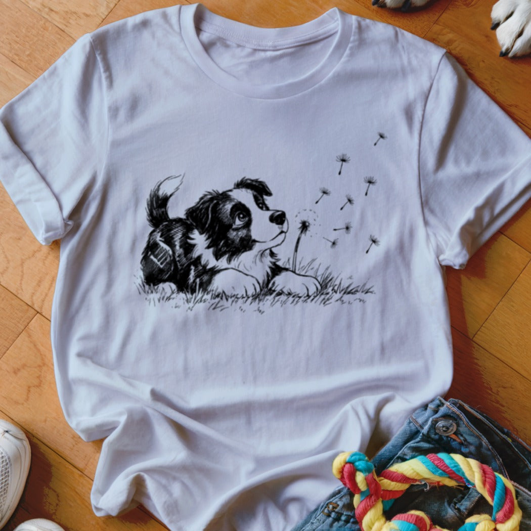 White t-shirt featuring a black and white sketch of a puppy watching dandelion seeds blow away.