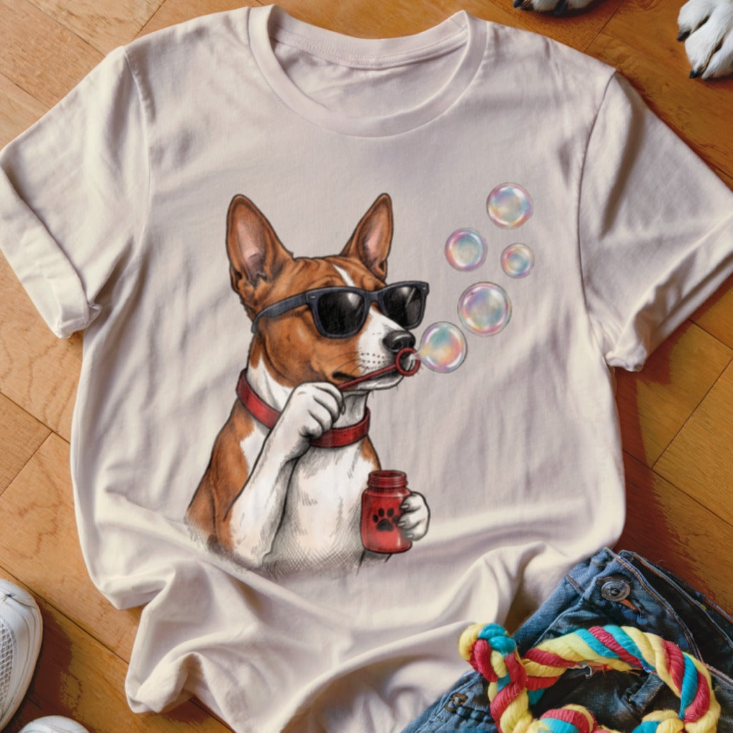 A beige t-shirt printed with an illustration of a brown and white dog wearing sunglasses and blowing bubbles.
