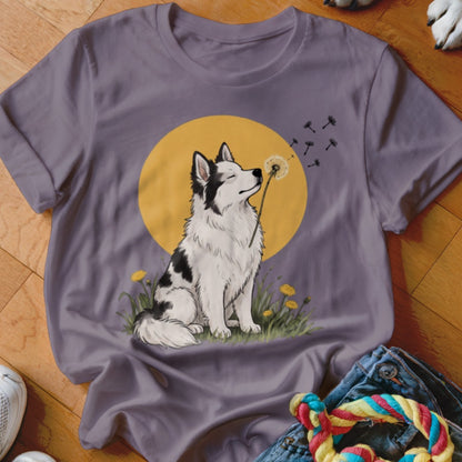 A purple t-shirt featuring an illustration of a black and white dog blowing dandelion seeds against a yellow circle background.