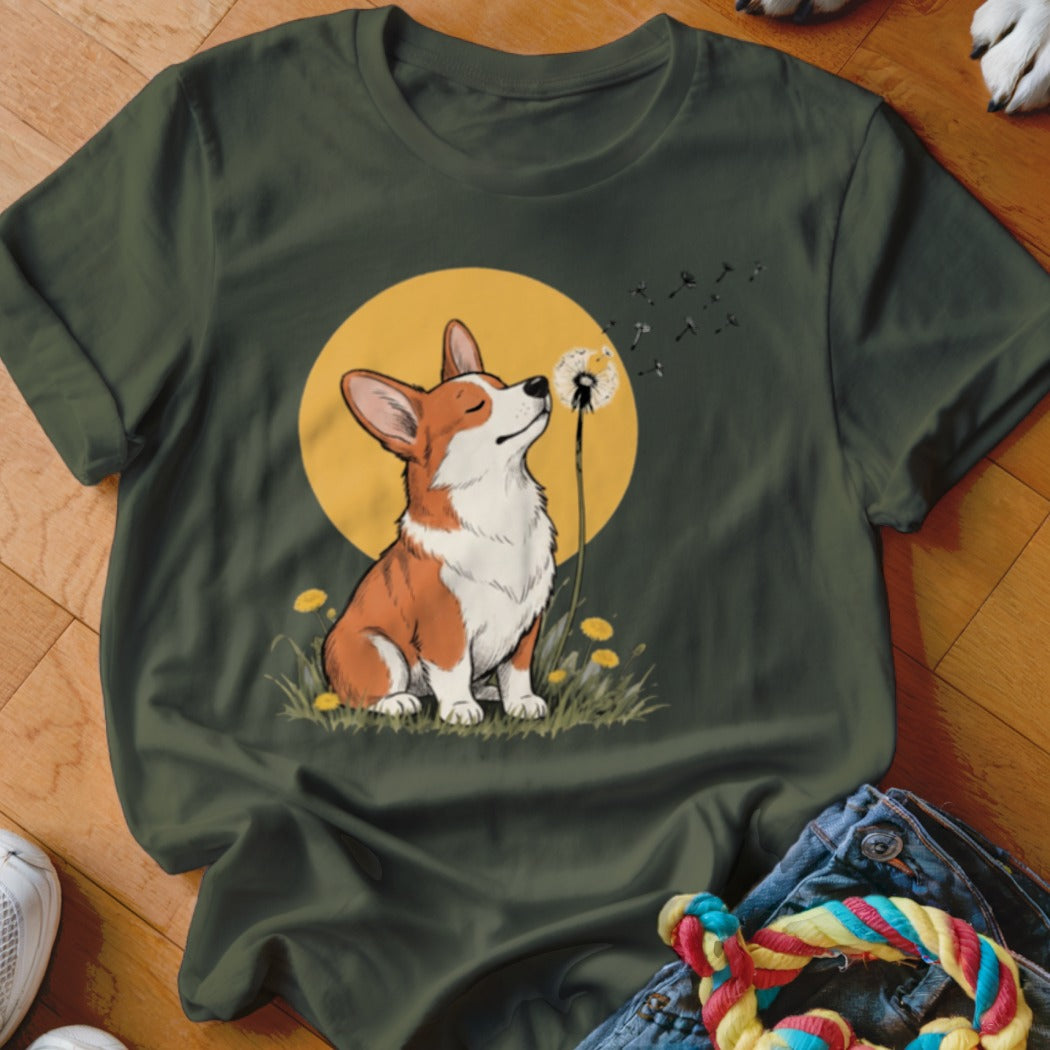 Dark green t-shirt featuring a graphic of a corgi blowing dandelion seeds against a yellow circle background.