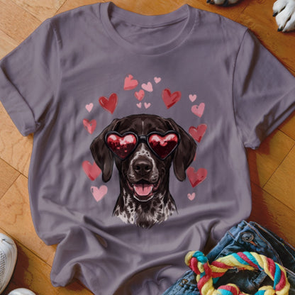 A grey crewneck t-shirt features a graphic of a spotted brown dog wearing heart-shaped sunglasses surrounded by pink hearts.