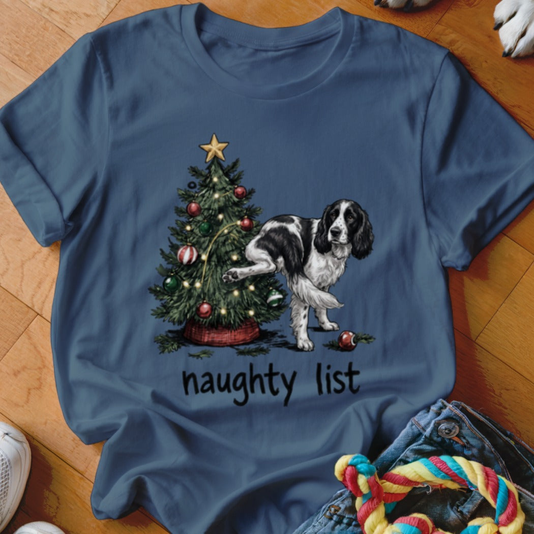 T-shirt with a black and white dog next to a decorated Christmas tree, reads "naughty list."