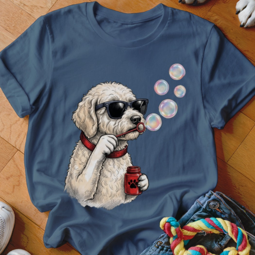 A blue t-shirt featuring a graphic of a white curly-haired dog wearing sunglasses and blowing bubbles.