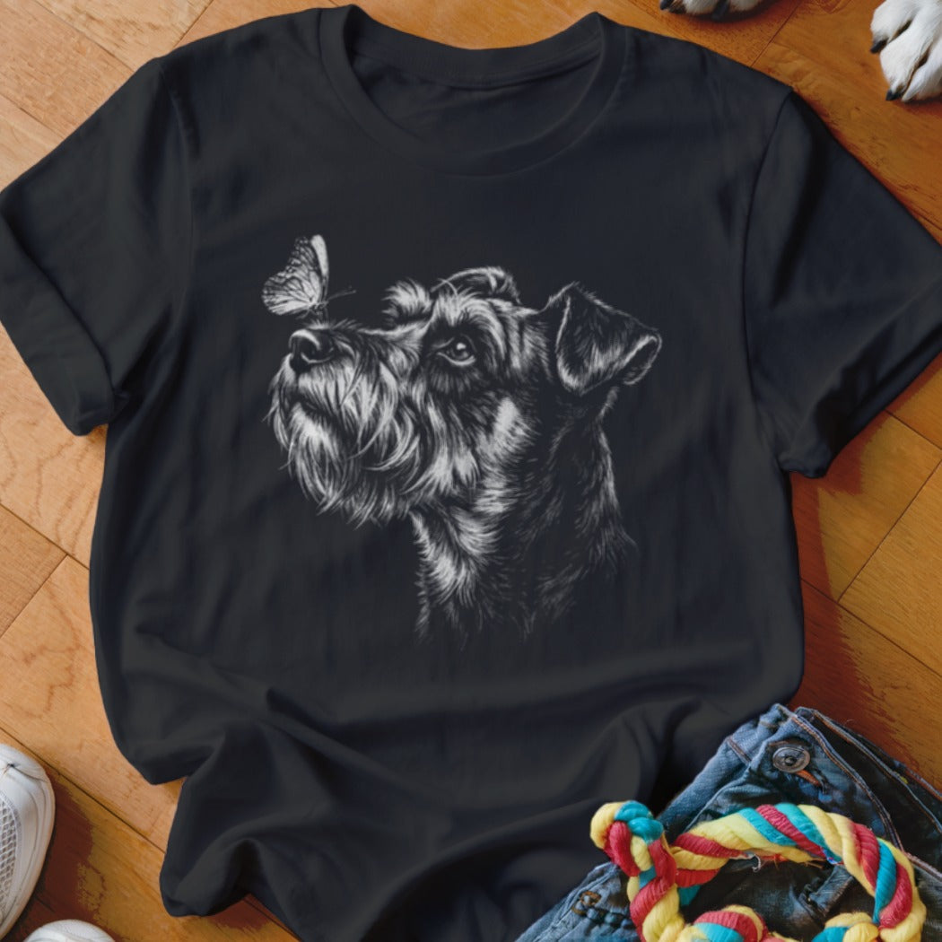 A black t-shirt features a white sketch of a schnauzer dog looking at a butterfly on its nose.