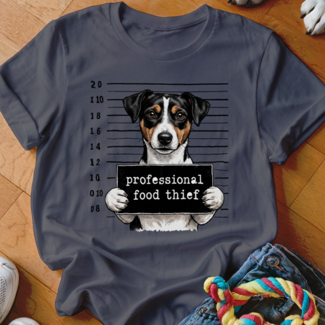 Jack Russell terrier in mugshot holding "professional food thief" sign.