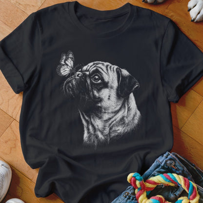 A black t-shirt printed with a detailed black-and-white sketch of a pug looking at a butterfly.
