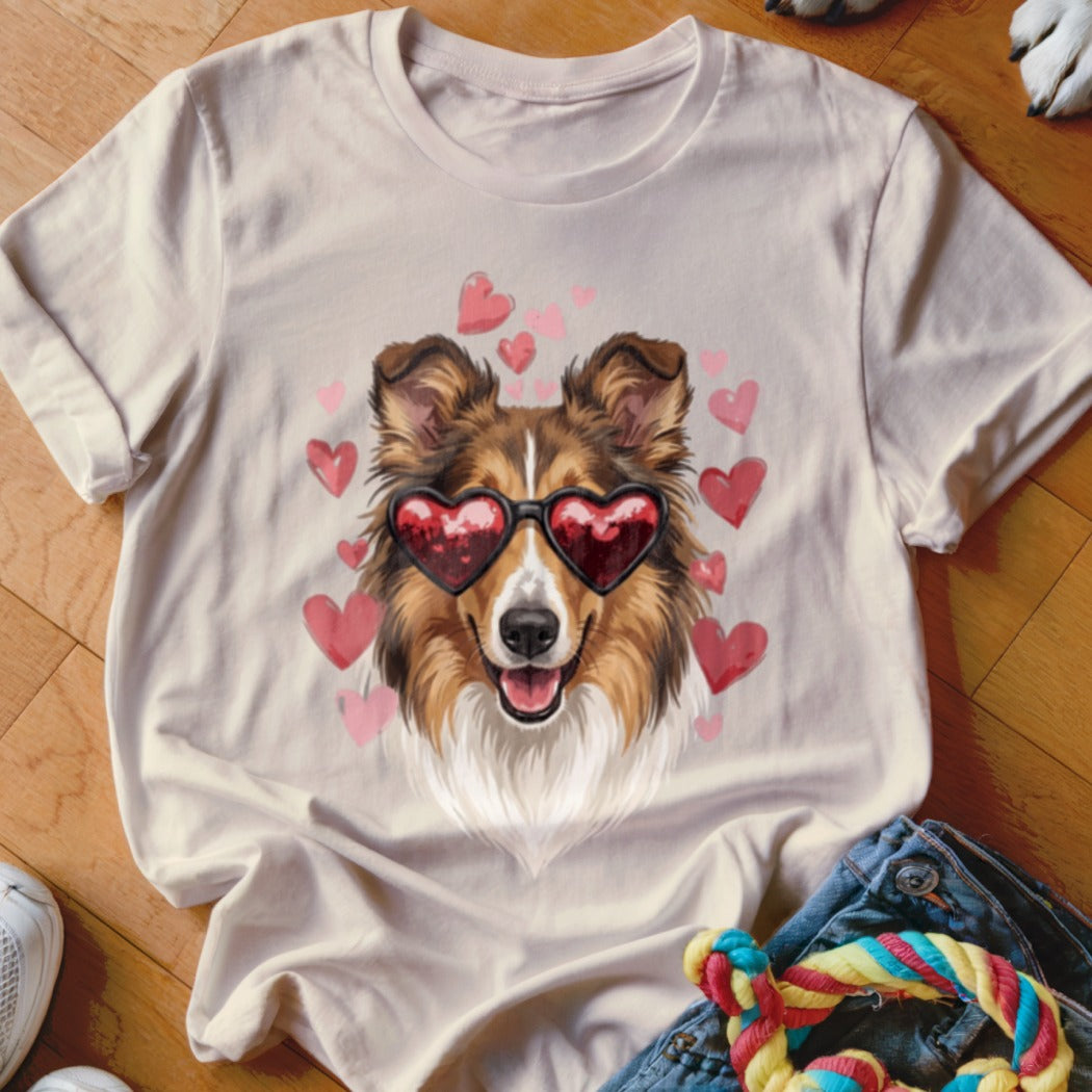 Light-colored t-shirt featuring a graphic of a Sheltie dog wearing heart-shaped sunglasses surrounded by pink hearts.