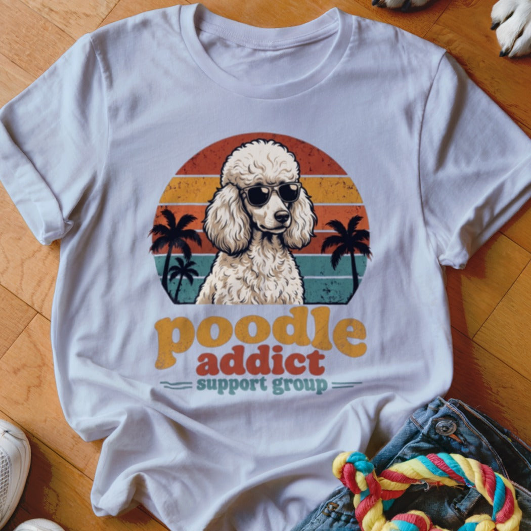A white t-shirt featuring a retro graphic of a poodle in sunglasses with palm trees and sunset stripes.